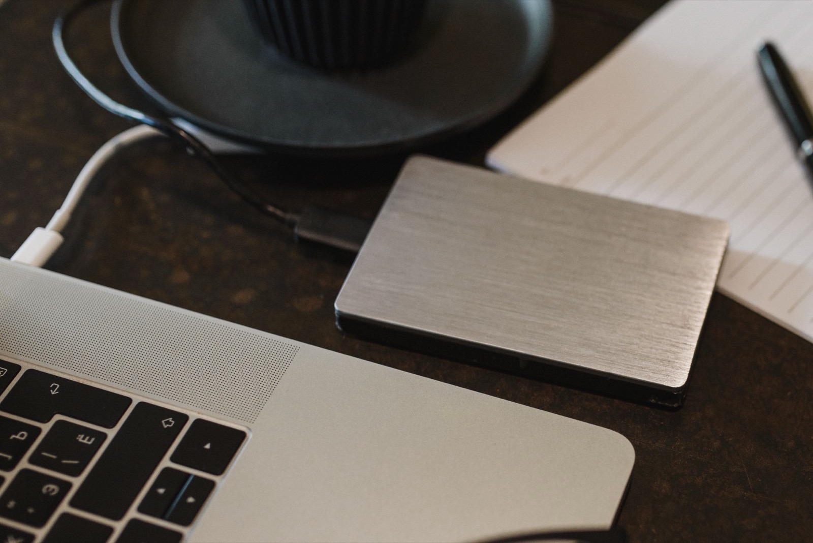 An external hard drive connected to a MacBook on a desk