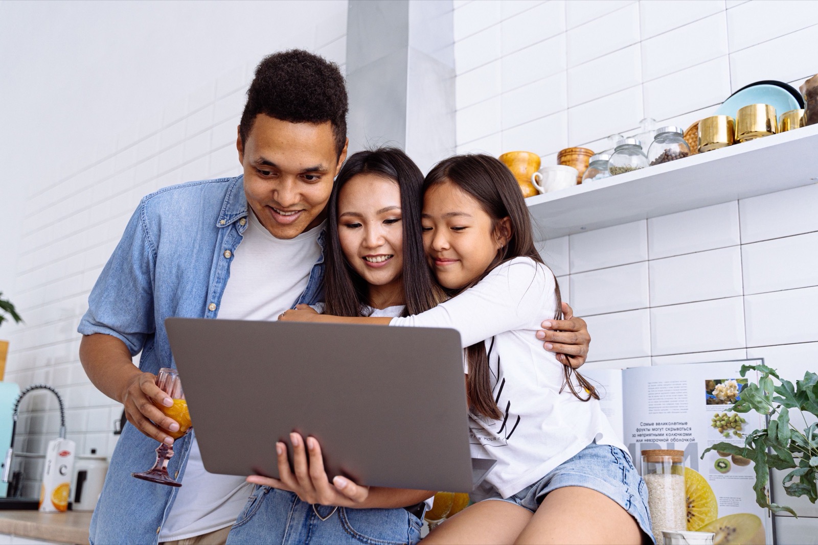 Eine Familie versammelt sich um einen Laptop und schaut sich gemeinsam alte Fotos an