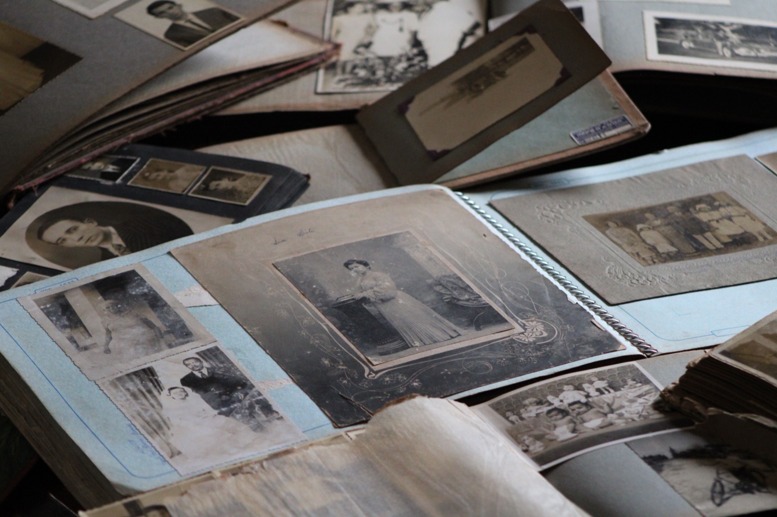 Une pile de vieux albums photo et de tirages détachés étalés sur une table