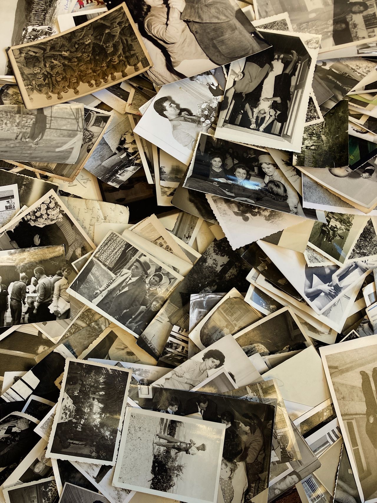 A dense pile of hundreds of vintage family photo prints